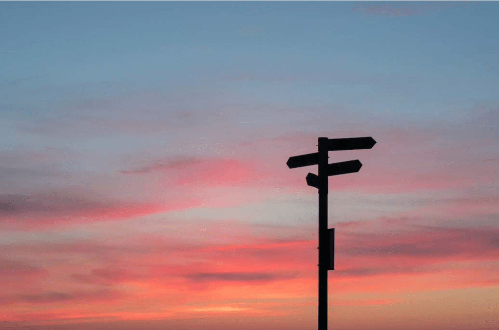 Coucher de soleil avec un panneau qui indique plusieurs directions
